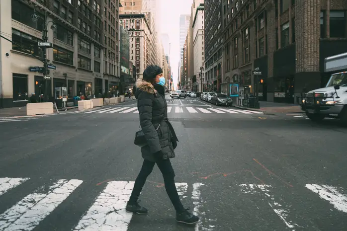 A woman in a winter coat walks in a crosswalk in New York City.